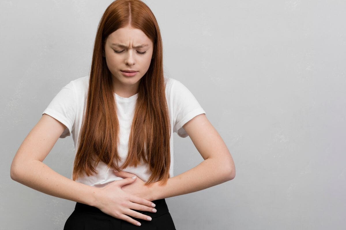 Egy orvos vizsgálja egy fiatal nő hasát, orvosi műszerekkel.