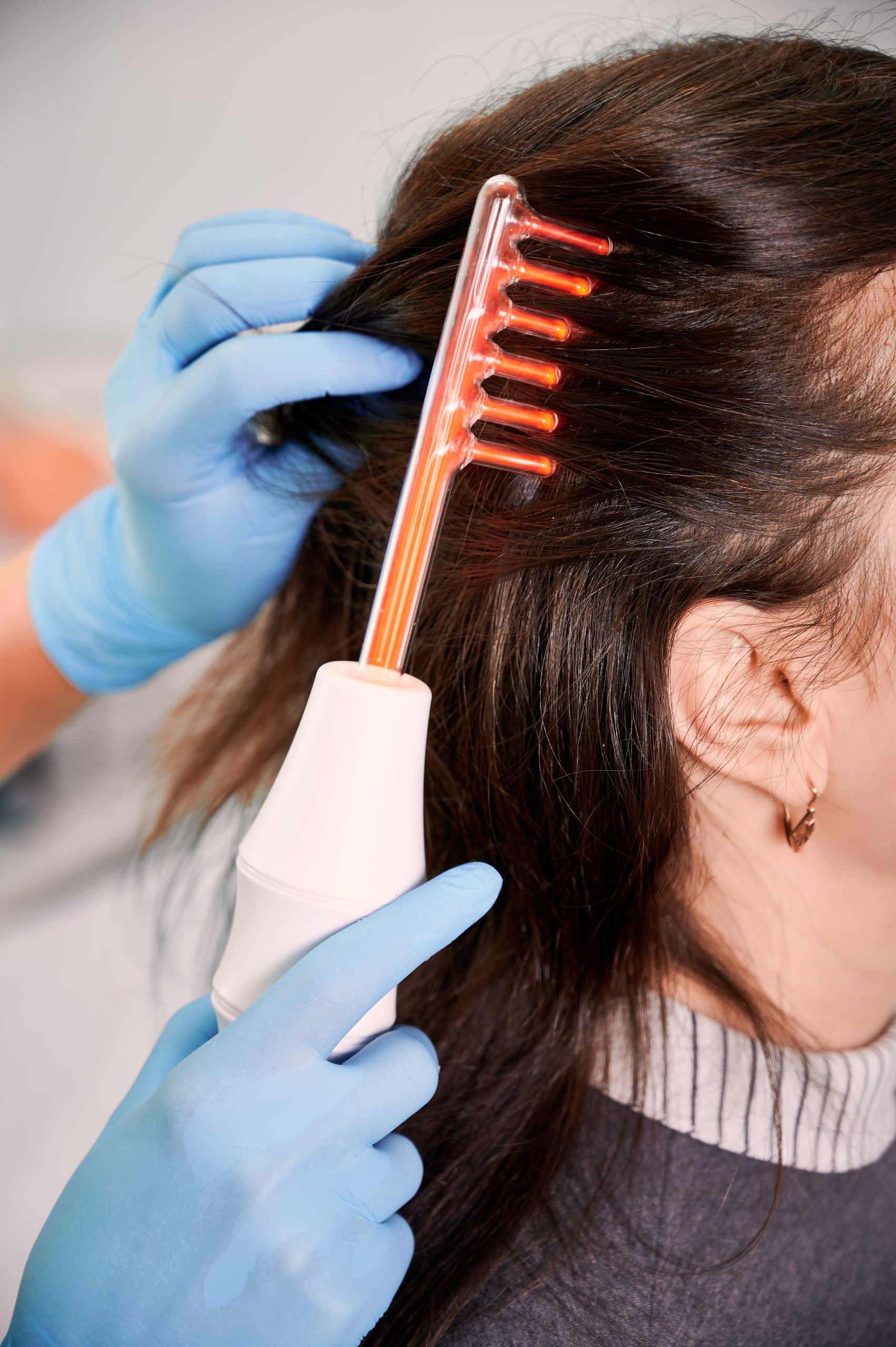 Hair specialist brushing woman hair with laser comb.